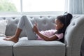 Girl using digital tablet on a sofa in living room Royalty Free Stock Photo