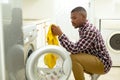 Man putting clothes in washing machine in kitchen at home Royalty Free Stock Photo