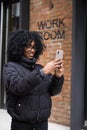 African american tourist woman visiting a new city street destination, using a smart phone taking pictures on holiday, outdoors. Royalty Free Stock Photo