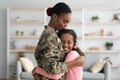 Side view of black mother in military uniform hugging child