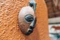 Side view of African mask on a orange stucco wall hanging for decoration. Shallow depth of field