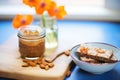 side view of almond butter on crusty bread, small bowl of almonds beside