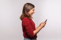 Side view, amazed brunette girl in shaggy sweater using mobile phone with surprised expression, reading shocking message Royalty Free Stock Photo