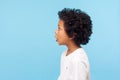 Side view of amazed little boy with curly hair looking in surprise at empty advertising space