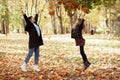Side view of funny family of young woman mother and teenage girl daughter jumping, throwing leaves in forest in autumn. Royalty Free Stock Photo