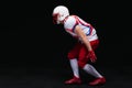 Side view of American football player wearing helmet taking position while playing against black background Royalty Free Stock Photo