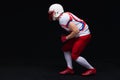 Side view of American football player wearing helmet taking position while playing against black background Royalty Free Stock Photo