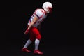 Side view of American football player wearing helmet taking position while playing against black background Royalty Free Stock Photo