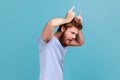 Side view of angry bully bearded man showing bull horn gesture with fingers over head. Royalty Free Stock Photo