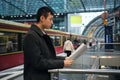 Side view of Asian businessman intently reading newspaper at subway station Royalty Free Stock Photo