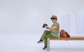 Asian female tourist checking photo on digital camera while sitting on wooden bench in white rest area of subway station Royalty Free Stock Photo