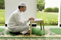 Side view of asian muslim man reading holy book koran Royalty Free Stock Photo