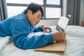 Side view of woman lying on white bed and writing notes Royalty Free Stock Photo