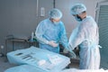 Side view of assistant male helping surgeon putting on latex gloves before operation. Team of surgeons in operating room Royalty Free Stock Photo