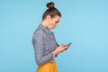 Side view of astonished mobile user, surprised woman with hair bun reading unexpected shocking message on cellphone Royalty Free Stock Photo