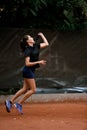 side view of an athletic female tennis player bouncing with racket and ready to hit tennis ball. Royalty Free Stock Photo