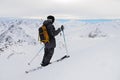 Side view of an athletic skier in a helmet and goggles with a backpack, standing on skis, holding ski poles in white Royalty Free Stock Photo