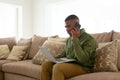 Man talking on mobile phone while using laptop on sofa in living room at comfortable home Royalty Free Stock Photo