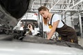 Female mechanic in white shirt and coverall repairing engine