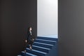 Side view of attractive thoughtful young european business woman walking in abstract concrete wall opening with blue stairs and Royalty Free Stock Photo