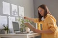 Side view of attractive woman with brown hair wearing yellow shirt posing in office, holding papers, pointing at graphs on the Royalty Free Stock Photo