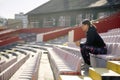 Side view of attractive young adult female sitting at the stadium. looking at distance with headphones in her ears, thinking