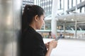 Side view of attractive young Asian woman holding mobile smart phone on the street of city. Social network concept Royalty Free Stock Photo