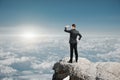 Side view of attractive young caucasian businessman standing on cliff and looking into the distance on bright blue sky and clouds Royalty Free Stock Photo