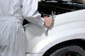 Side view of automotive mechanic in uniform with wrench diagnosing engine under hood of car at the repair garage. Royalty Free Stock Photo