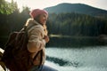 Side view backpacker smiling woman admiring mountain lake among forest Royalty Free Stock Photo