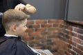 Side view. The barber's hands cut the boy's hair. The boy, as an adult, sits in a chair in a barbershop and