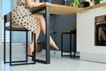 Side view of barefoot female legs under the table