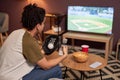 Side view baseball fan holding TV remote while watching match at home