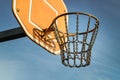 Side view of Basketball backboard with the hoop metal ring and steel chain net against blue sky background seen from below Royalty Free Stock Photo
