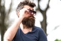 Side view bearded man adjusting his sunglasses. Stylish young man with well-trimmed beard and mustache enjoying warm