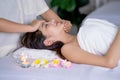 Side view of beaudiful Asian woman lie on bed for massage and spa process with massesuse treat with hands on woman face in room Royalty Free Stock Photo