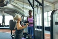 Trainer assisting active senior woman on lat pulldown machine in fitness studio