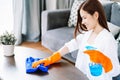 Side view of beautiful Asian woman wearing protective rubber gloves cleaning table at living room. People, housework and