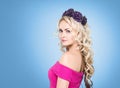 Beauty portrait of attractive blond girl with curly hair and a beautiful headband over blue background.