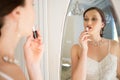 Side view of beautiful bride applying lipstick reflecting on mirror