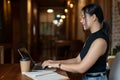 Side view of a beautiful Asian businesswoman is working on her laptop in a coffee shop Royalty Free Stock Photo