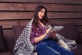 Side view of beautiful girl in casual clothes under blanket making notes while sitting on the sofa Royalty Free Stock Photo