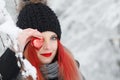 Side view of a beautiful girl covering one eye with a red heart outdoors Royalty Free Stock Photo