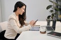 Side view of a beautiful Asian businesswoman using her phone at her desk in the office Royalty Free Stock Photo