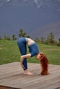 side view beautiful redhead yoga woman in leggings and sport top is practicing yoga exercises Royalty Free Stock Photo