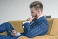 Side view of beautiful sexy businessman sitting on a sofa in a suit and using his phone