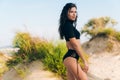 Side view of a beautiful slender young European-looking girl in a stylish separate swimsuit with a closed top posing on Royalty Free Stock Photo