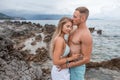 side view of beautiful tender young couple in love hugging and kissing on rocky beach Royalty Free Stock Photo