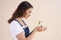 Side view of beautiful woman holding small seedling