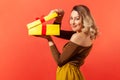 Side view beautiful woman unpacking big yellow gift box and looking at camera with pleasant smile, satisfied with present Royalty Free Stock Photo